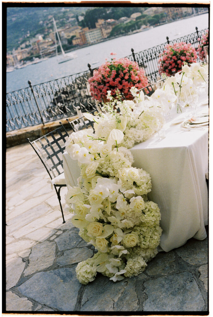 Film photograph close-up of a cascading white floral table runner with roses, hydrangeas, and orchids